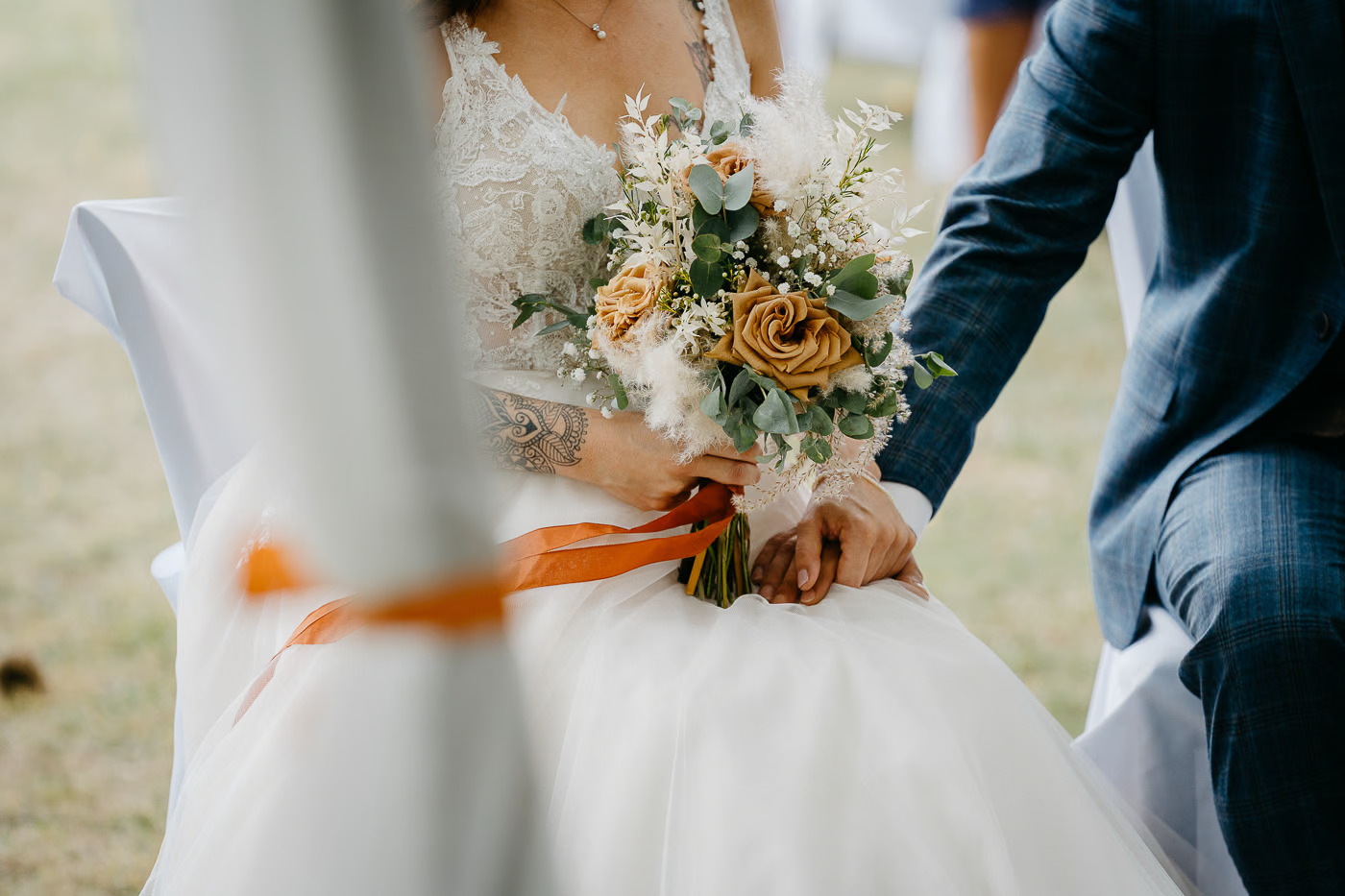 Freie Trauung Wolfsburg – Detailaufnahme Brautstrauß mit senfgelben Rosen und Pampagras, Hand der Braut mit Tattoo sichtbar, Hochzeitsdetail freie Trauung Wolfsburg Kathrin Skorpel