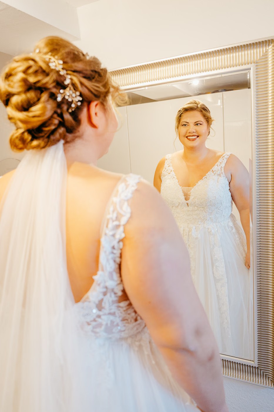 Getting Ready Hochzeit – strahlende Braut im Hochzeitskleid blickt in den Spiegel, fertig angezogen kurz vor der Trauung, Hochzeitsfotos Peine Kathrin Skorpel
