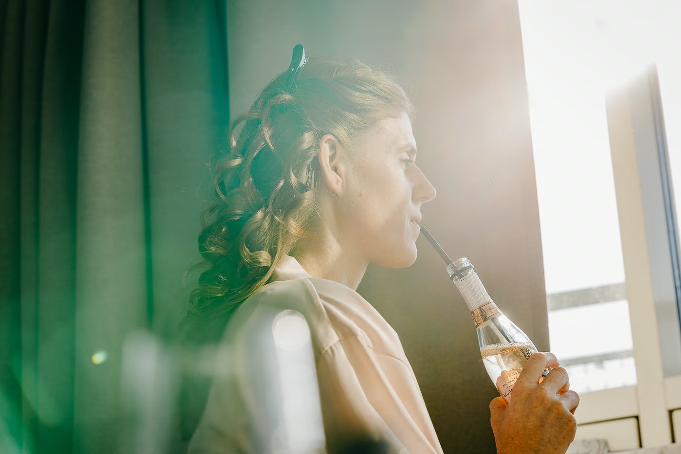 Getting Ready Hochzeit – Braut trinkt Sekt mit Strohhalm während des Frisierens, entspannte Atmosphäre vor der Trauung, Hochzeitsfotografin Wolfenbüttel Kathrin Skorpel