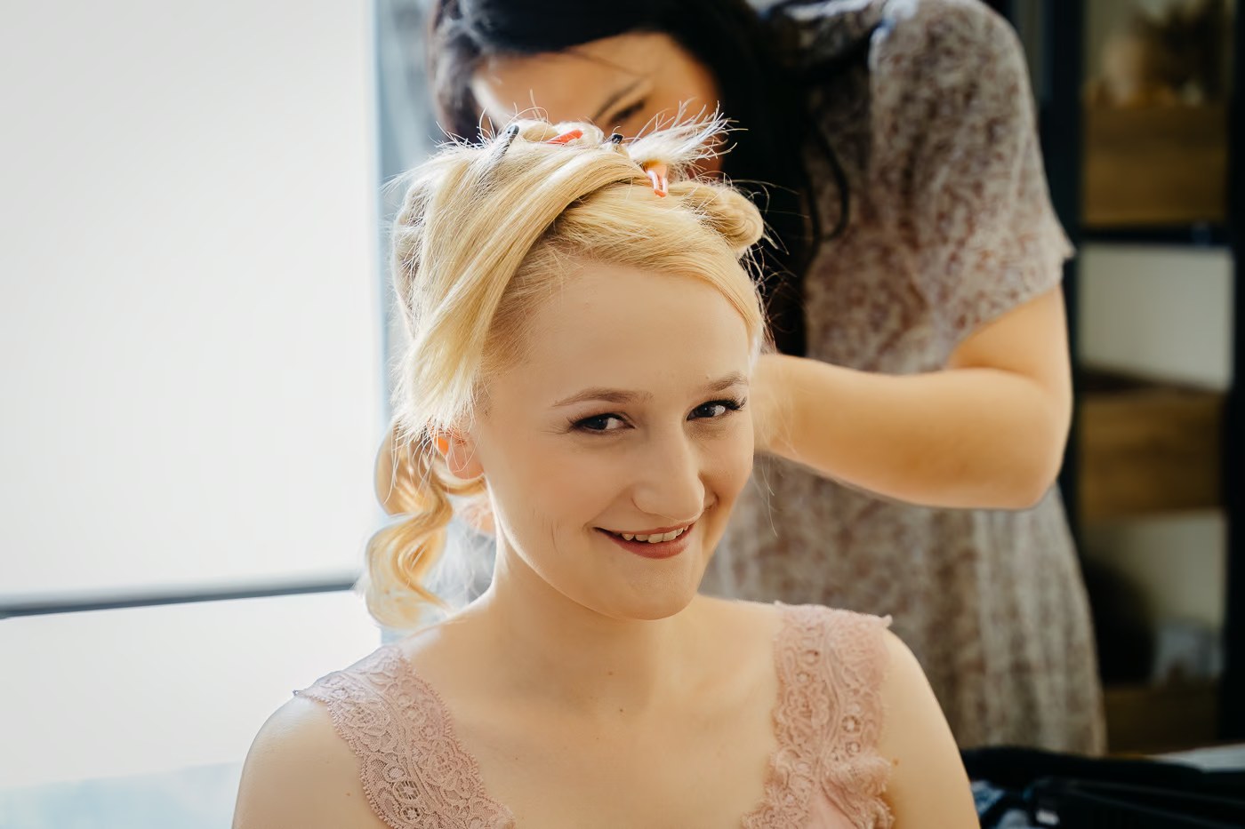 Getting Ready Hochzeit – Braut lächelt strahlend beim Frisieren, Hochsteckfrisur wird gesteckt, authentische Hochzeitsreportage Braunschweig Kathrin Skorpel