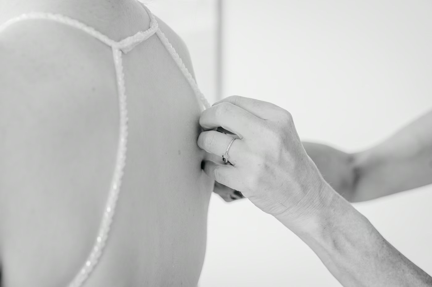 Getting Ready Hochzeit – Träger des Brautkleides wird liebevoll eingefädelt, Schwarz-Weiß Detailaufnahme, Hochzeitsfotografie Braunschweig Kathrin Skorpel