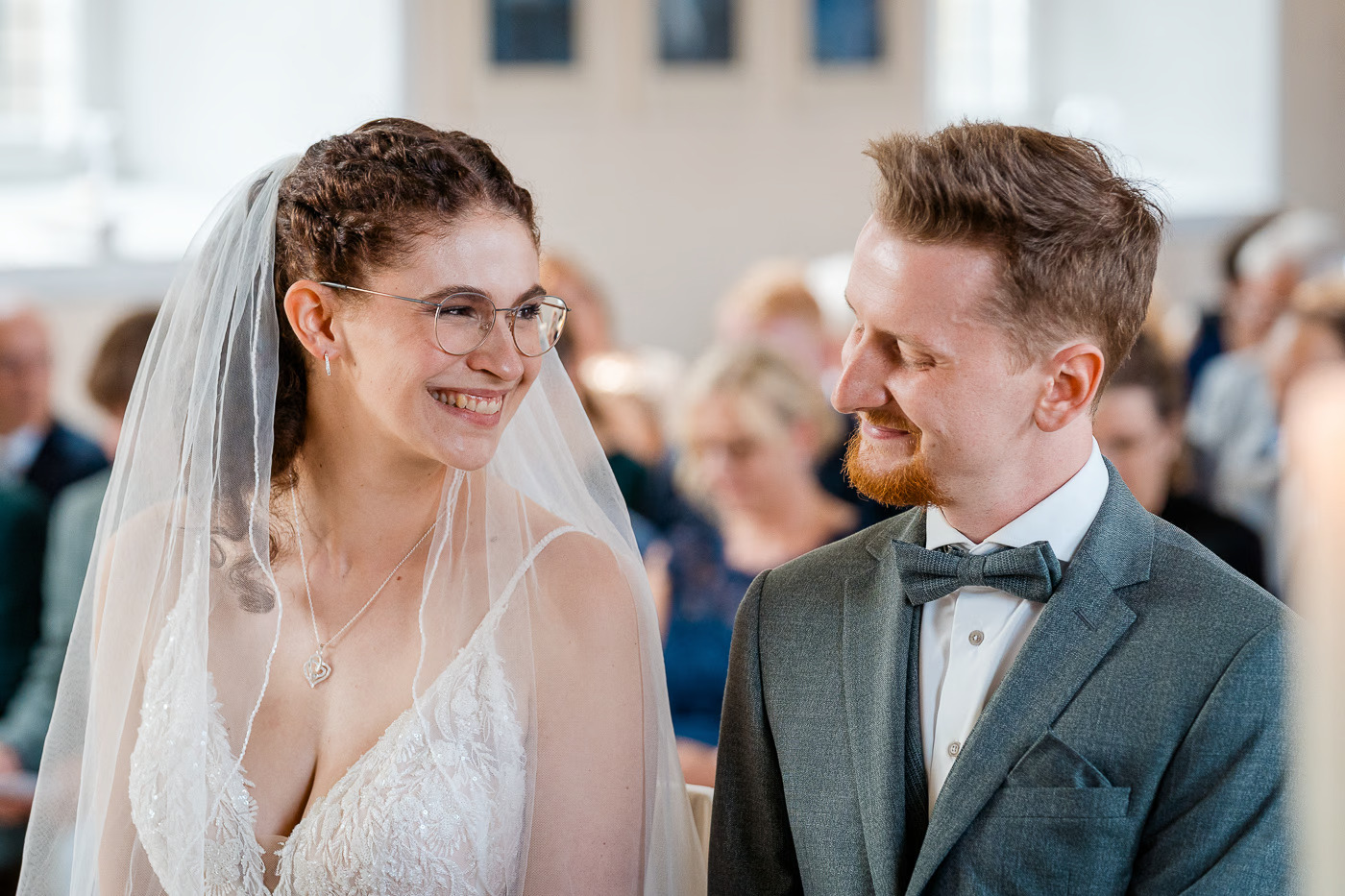 Kirchliche Trauung Braunschweig – Braut mit Brille und Schleier lächelt Bräutigam an, beide strahlen während der Trauung, authentische Hochzeitsreportage Braunschweig Kathrin Skorpel