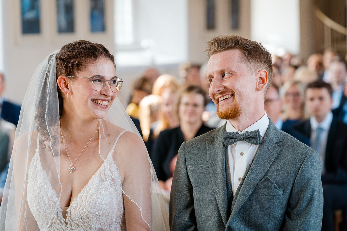 Kirchliche Trauung Helmstedt – Brautpaar lacht ausgelassen in der Kirche, Hochzeitsgäste im Hintergrund, pure Freude und Glück bei der kirchlichen Hochzeit Helmstedt Kathrin Skorpel