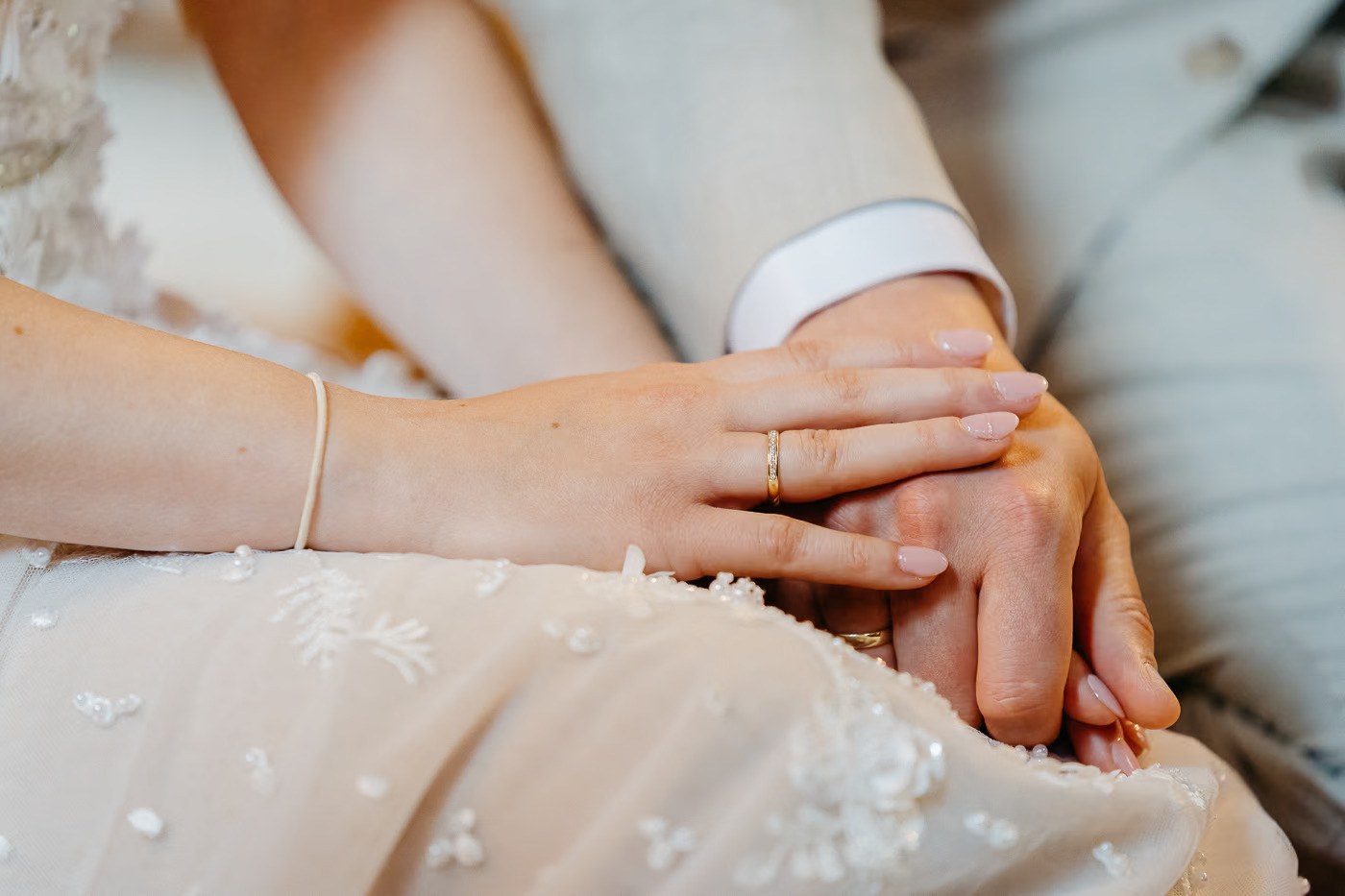 Kirchliche Trauung Wolfenbüttel – Detailaufnahme der Hände des Brautpaares mit goldenen Eheringen auf dem Brautkleid, zarter Ringschmuck, Hochzeitsdetails Wolfenbüttel Kathrin Skorpel