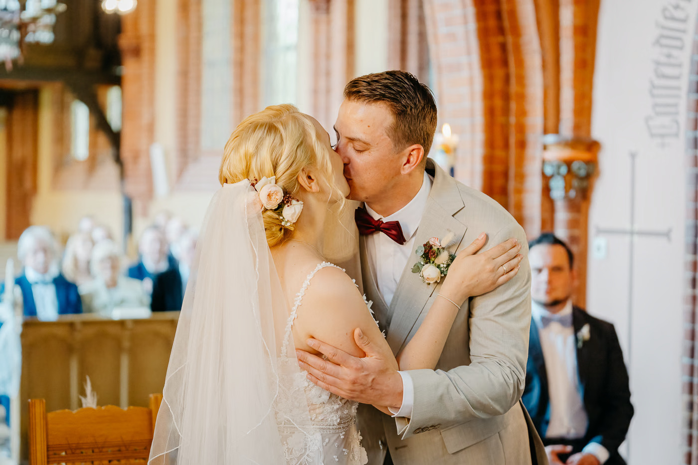 Kirchliche Trauung Helmstedt – Brautpaar küsst sich zum ersten Mal als Ehepaar vor dem Altar, Braut mit Blumen im Haar und Schleier, inniger Hochzeitskuss Helmstedt Kathrin Skorpel