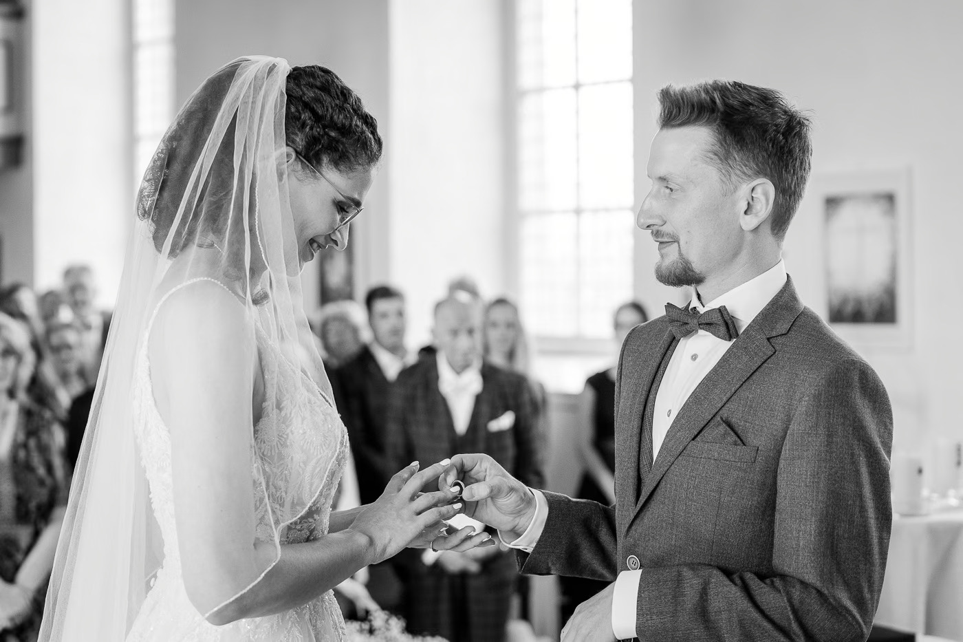 Kirchliche Trauung Braunschweig – Braut steckt dem Bräutigam den Ehering auf den Finger, beide lächeln bewegt, Ringtausch kirchliche Hochzeit Braunschweig Kathrin Skorpel