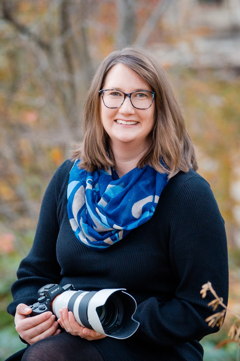 Portrait Kathrin Skorpel Wolfenb&uuml;ttel – Fotografin mit Kamera l&auml;chelt herzlich in herbstlicher Umgebung, Hochzeitsfotografin Wolfenb&uuml;ttel Kathrin Skorpel