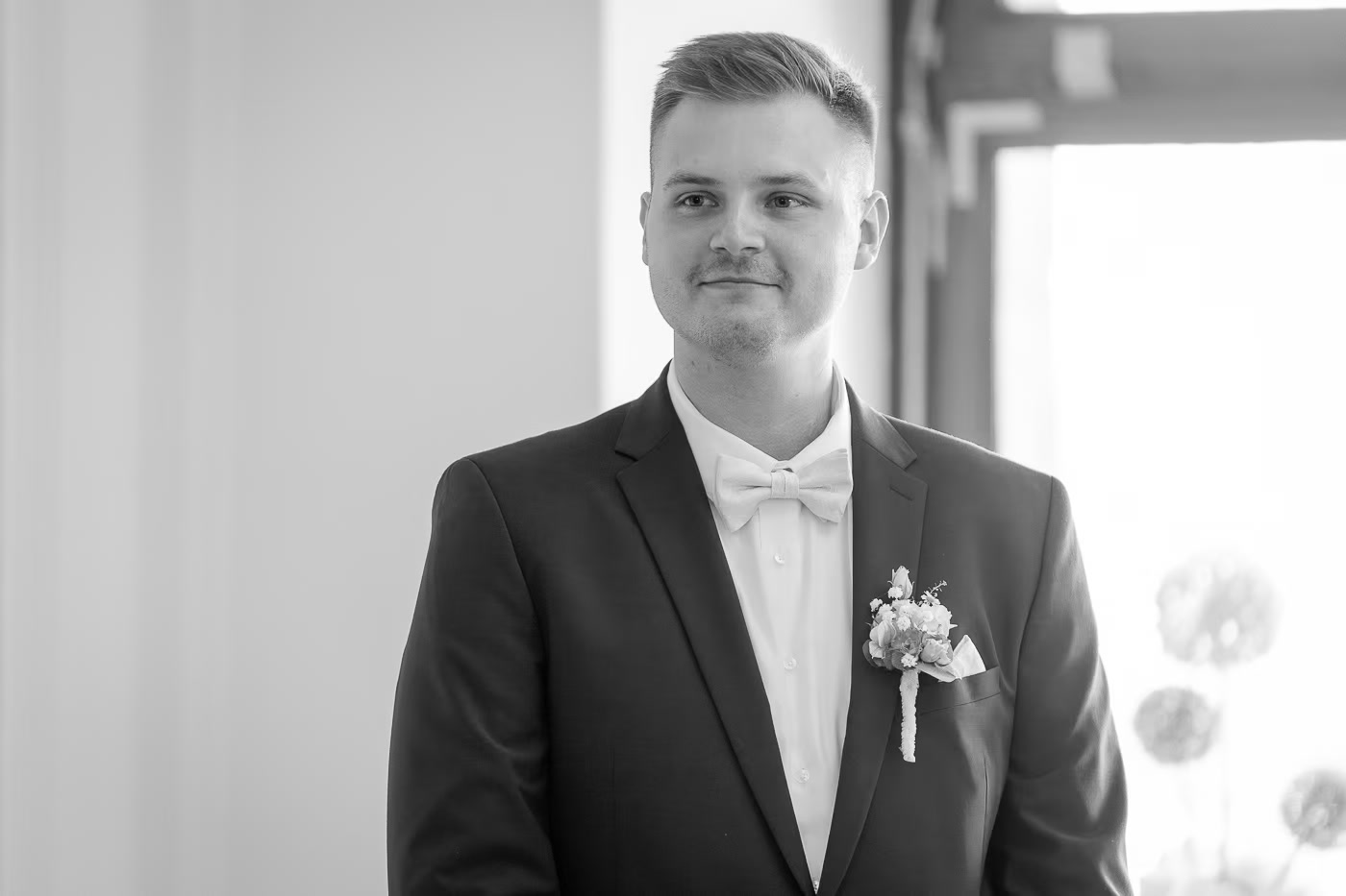 Standesamt Hochzeit Braunschweig – Schwarz-Weiß Portrait Bräutigam im dunklen Anzug mit weißer Fliege und Ansteckblume, ruhige Eleganz vor der Trauung, Hochzeitsfotografie Braunschweig Kathrin Skorpel