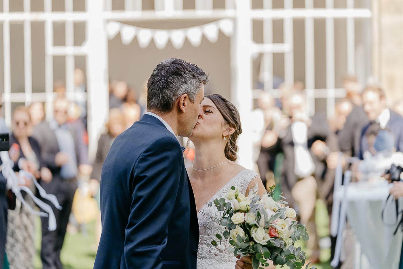 Standesamt Hochzeit Salzgitter – Brautpaar küsst sich beim ersten Kuss im Pavillon umgeben von jubelnden Gästen und Wimpelkette, bewegender Moment nach dem Ja-Wort, Hochzeitsreportage Salzgitter Kathrin Skorpel