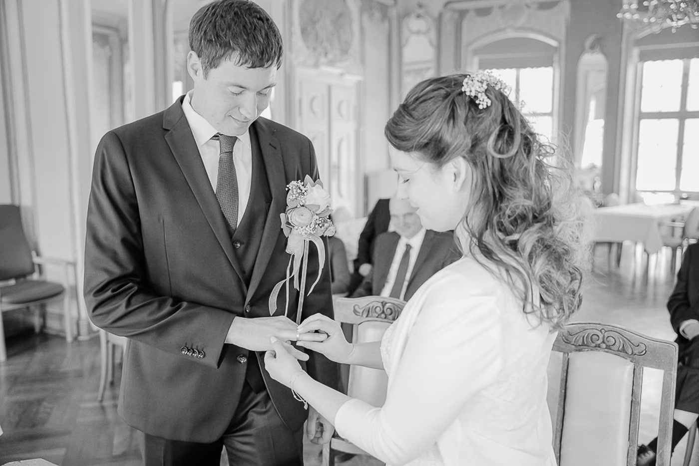 Standesamt Hochzeit Braunschweig – Schwarz-Weiß Aufnahme Ringtausch im historischen Trausaal, Braut steckt dem Bräutigam den Ring an, beide blicken konzentriert auf die Hände, Hochzeitsreportage Braunschweig Kathrin Skorpel
